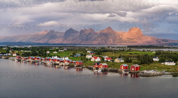 Boathouses of the village Herøy, behind the mountain range Seven Sisters, light mood, island Herøy,