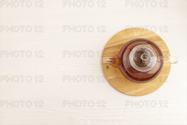Red tea with herbs in glass teapot on white wooden background. Healthy drink concept. Top view,