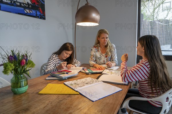 Homeschooling, during the lockdown in January 2021, mother helps her two daughters, at home,