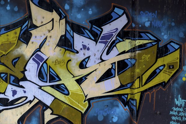 Graffiti artwork in blue and yellow with the year 2016 visible on an urban wall,