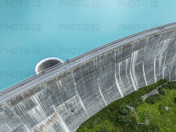 Dam of the Moiry lake, Lac de Moiry, turquoise glacial water, water overflow, tourists, aerial