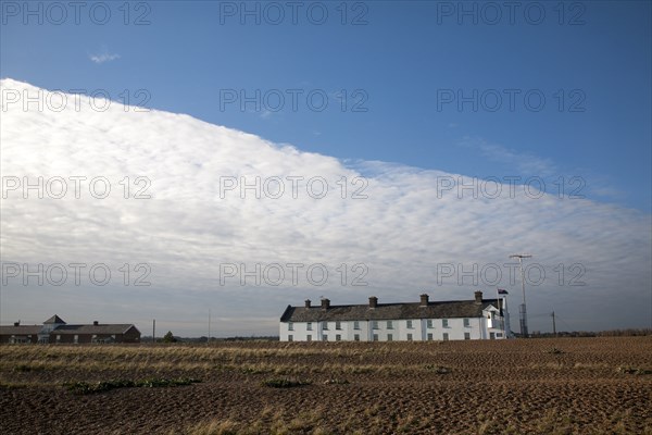 Frontal clouds passing over Coastguard Cottages shingle beach at Shingle Street, Suffolk, England,