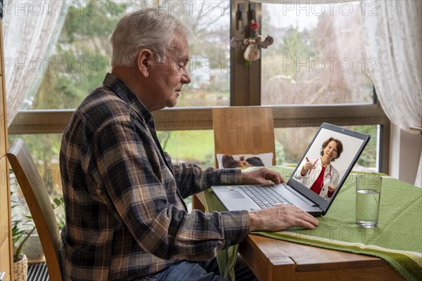 Symbolic image of telemedicine, elderly patient speaking to a doctor in a video conference from