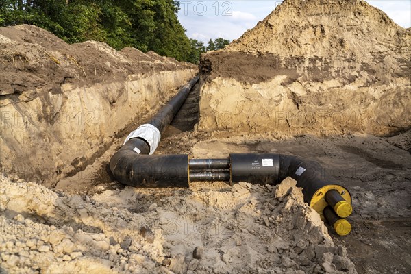 Laying of district heating pipes, next to a field, with maize, the district heating comes from a