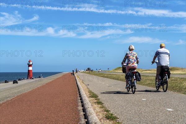North Sea dyke near Westkapelle, Westkapelle Laag lighthouse, cyclists on the Zeeuwse Wind Route