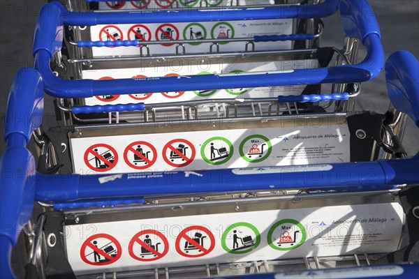Close up of line of stacked luggage trolleys with rules about use, Malaga airport, Spain, Europe