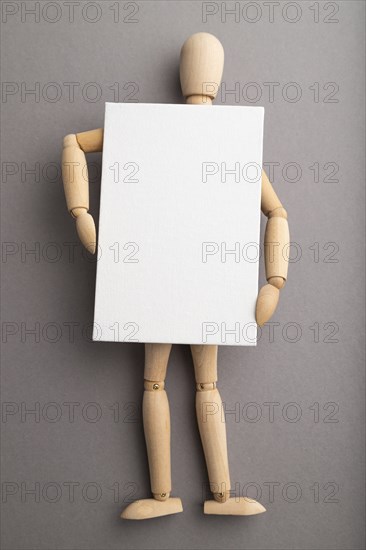 Wooden mannequin holding blank poster on gray pastel background. copy space, isolated, presentation
