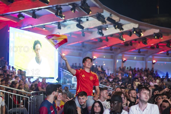 Fan of the Spanish team waving a flag at the Adidas fan zone at the Bundestag during the final