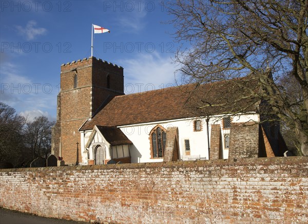 Red cross of flag of St George flying from tower of village Saint Peter church, Levington, Suffolk,