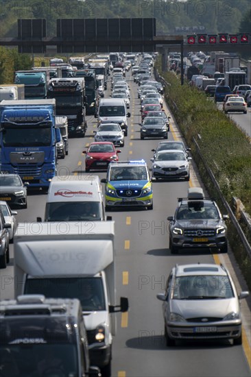 Police patrol car with flashing blue lights and siren working its way through a traffic jam on the