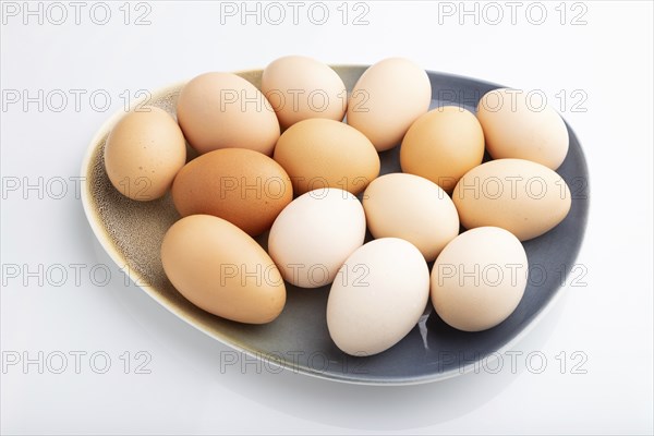 Pile of colored chicken eggs on plate isolated on white background. side view, close up