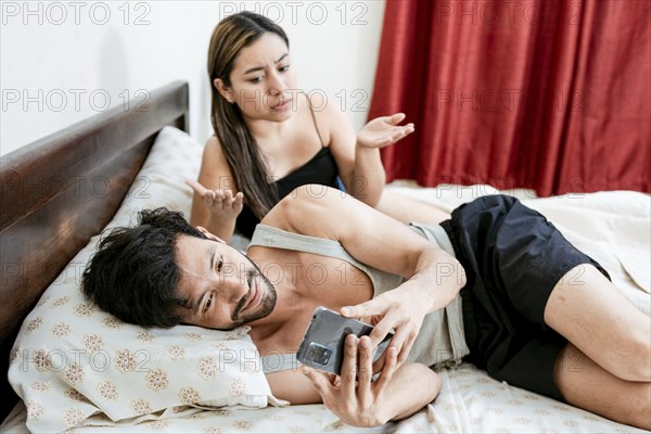 Cheating Husband Texting On Phone Ignoring Wife Lying In Bed. Husband with cell phone ignoring wife