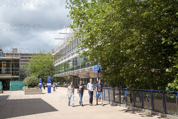 Male students walking on campus near the library building at the University of Bath, England,