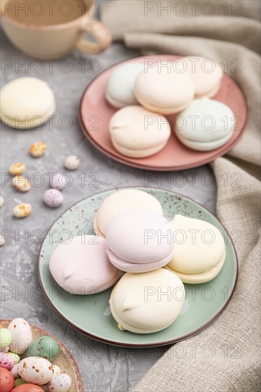 Colored zephyr or marshmallow with cup of coffee and dragees on a gray concrete background and