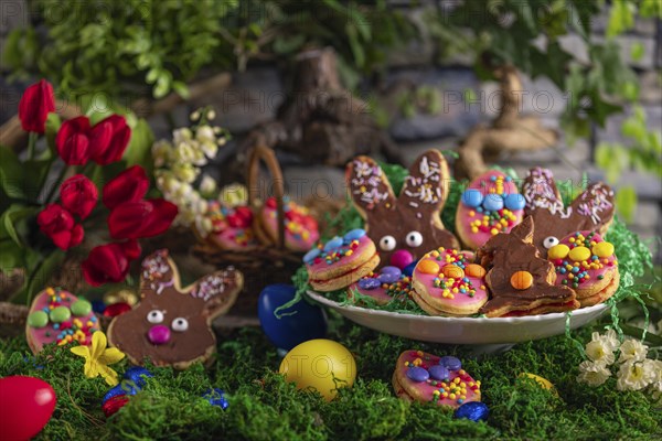 Colourful Easter biscuits with a bouquet of tulips and Easter eggs, arranged on a moss-covered