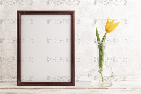 Wooden frame with orange tulip flower in glass on gray concrete background. side view, copy space,