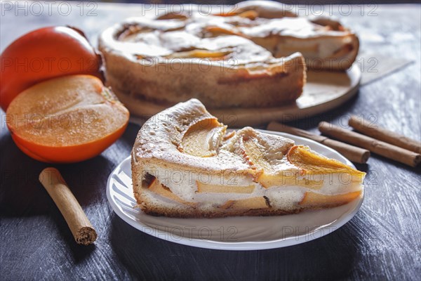 A slice of sweet persimmon pie on black wooden background. close up