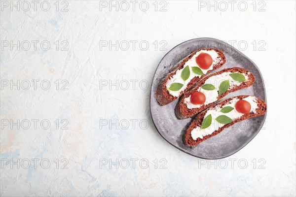Red beet bread sandwiches with cream cheese and tomatoes on white concrete background. top view,