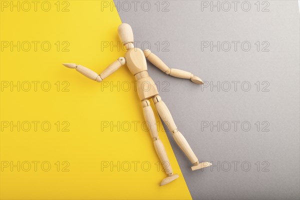 Wooden mannequin lies on gray and yellow pastel background. copy space, isolated, presentation