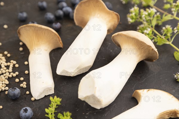 King Oyster mushrooms or Eringi (Pleurotus eryngii) on black concrete background with blueberry,