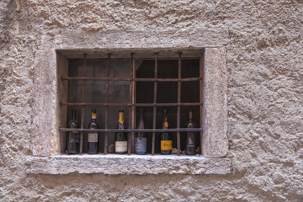 Barred window with empty champagne and wine bottles, Malcesine, Lake Garda, Province of Verona,