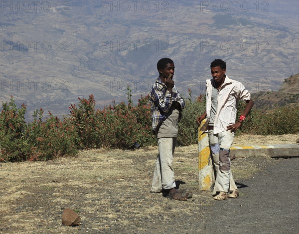 Landscape in the Choke Mountains, two young people waiting for the bus by the road, Ethiopia,