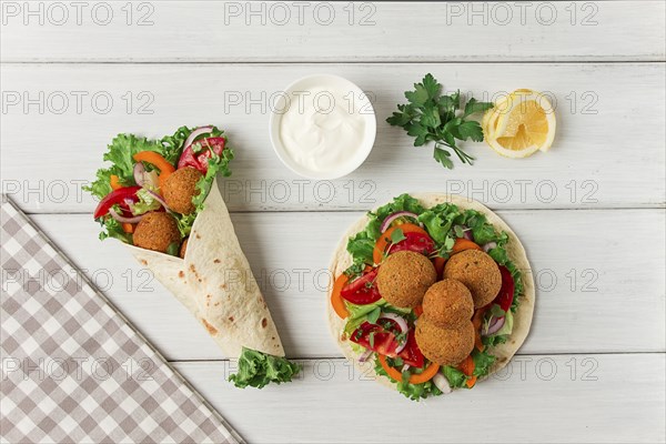 Tortillas, wrapped falafel balls, with fresh vegetables, vegetarian healthy food, on a wooden white