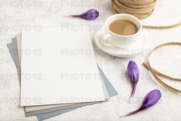 White paper sheet mockup with spring snowdrop crocus flowers and cup of coffee on gray concrete