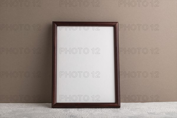 Brown wooden frame mockup on beige paper background. Blank, vertical orientation, still life, copy