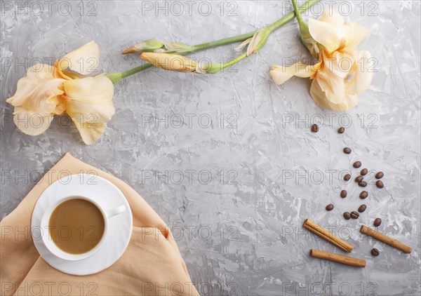 Orange iris flowers and a cup of coffee on a gray concrete background. Morninig, spring, fashion