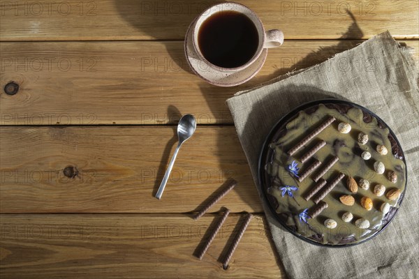 Homemade chocolate brownie cake with caramel cream and almonds with cup of coffee on wooden