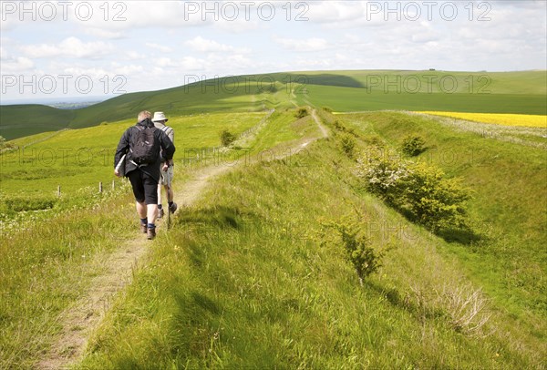 Two men walking along the ditch and embankment of the Wansdyke a Saxon defensive structure on All