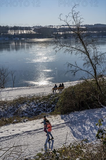 Winter in the Ruhr area, Lake Baldeney, snow-covered, partly frozen lake, walkers on the lakeside