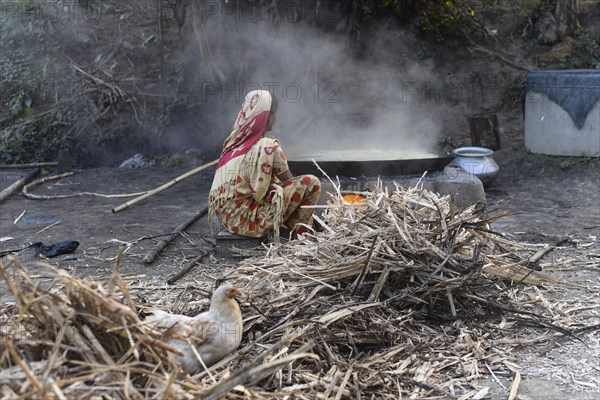 Workers boiling sugarcane juice as they are making Gur (jaggery) in a village on December 10, 2021