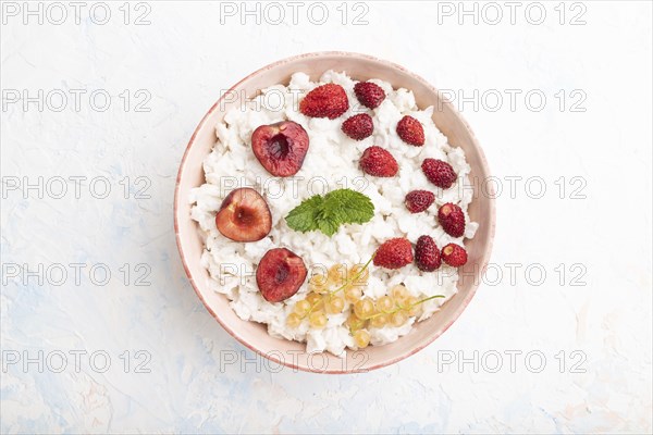 Rice flakes porridge with milk and strawberry in ceramic bowl on white concrete background. Top