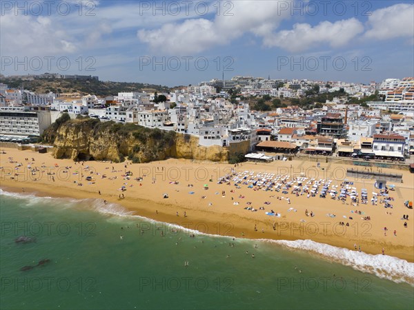 Coastal town with sandy beach, many bathers and buildings along the coast, aerial view, Albufeira,