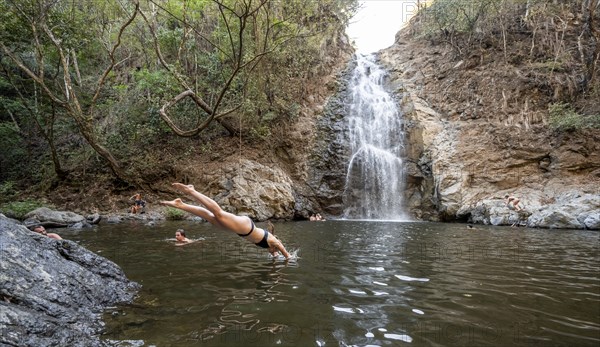 Young woman jumping into the water, Cascada Montezuma waterfall, Montezuma, Nicoya Peninsula,