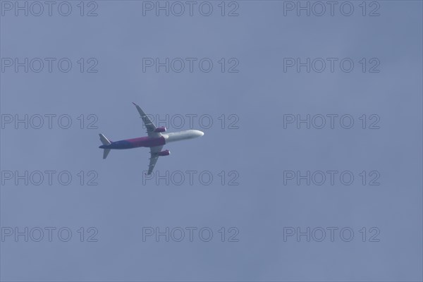 Airbus A320 aircraft of Wizz air airlines in flight across a blue sky, England, United Kingdom,
