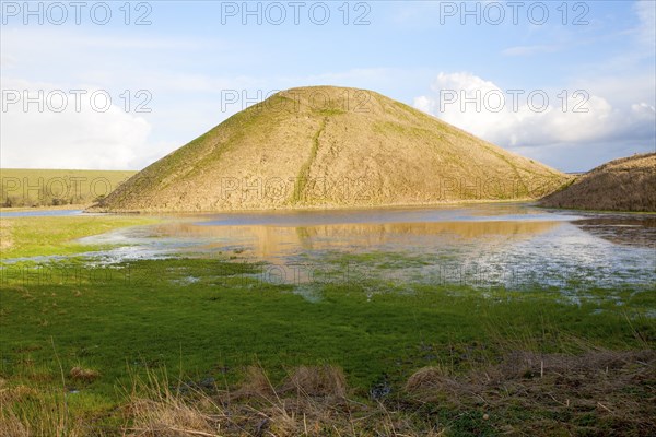 Silbury Hill ancient neolithic manmade chalk mound in Avebury, Wiltshire, England with flood water