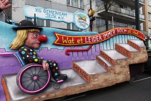 Wheelchair user in jester's costume waiting in front of steps, papier-mâché figure, motif float on