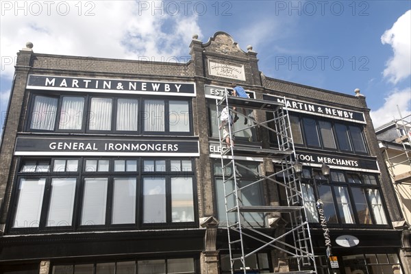 Painters working on scaffolding painting the Martin and Newby ironmongers shop building in Ipswich,