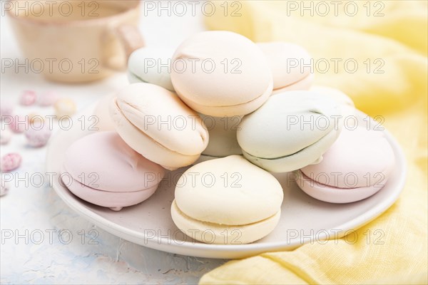 Colored zephyr or marshmallow with cup of coffee and dragees on white concrete background and