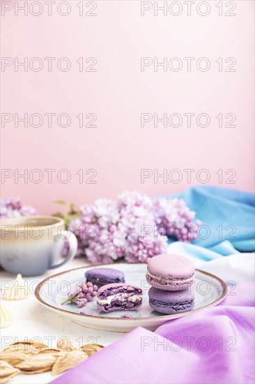 Purple macarons or macaroons cakes with cup of coffee on a white and pink background and