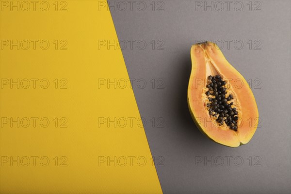 Ripe cut papaya on yellow and gray pastel background. Top view, flat lay, copy space. Tropical,