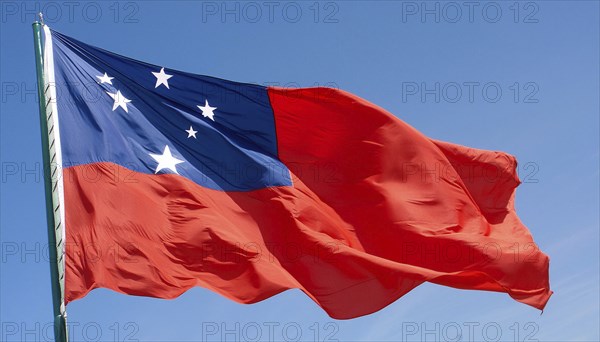 The flag of Samoa, fluttering in the wind, isolated against a blue sky