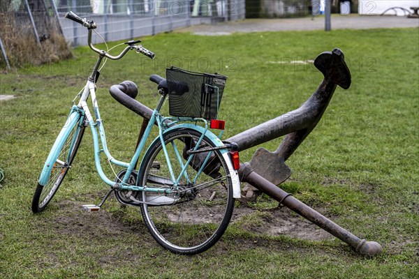 Bicycle, ladies' bicycle, well secured with a bicycle lock to an iron ship's anchor, in