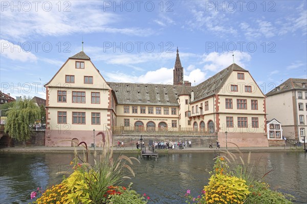 Musée historique, historical museum and river Ill with floral decoration, church tower of the
