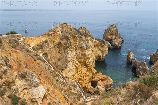 Rocks and a footpath with steps overlooking the picturesque coastline and the vast sea, Ponta da
