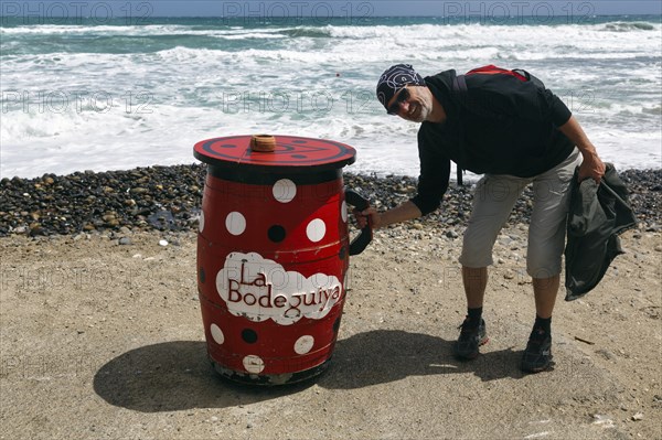 Red outdoor bar table, hiker, tourist holding jug, bar, beach bar, Cabo de Gata Natural Park,