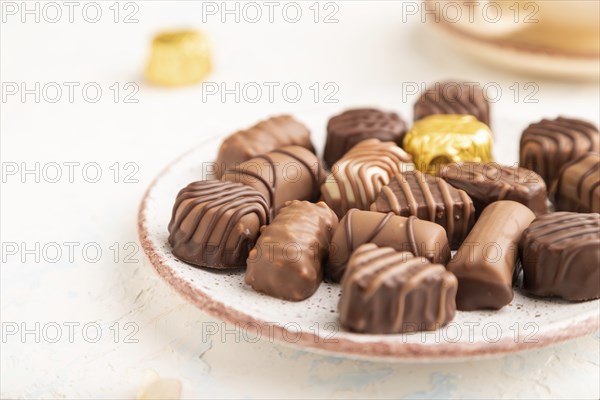 Chocolate candies with cup of coffee and hydrangea flowers on a white concrete background. side